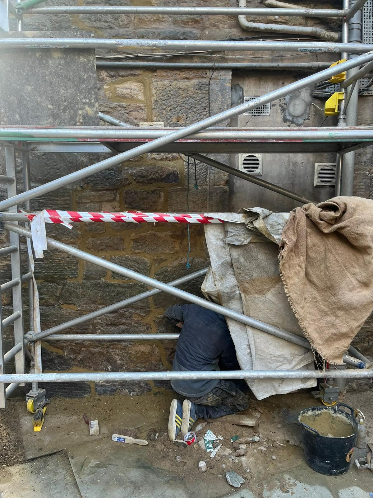 Stone repointing in progress under scaffold