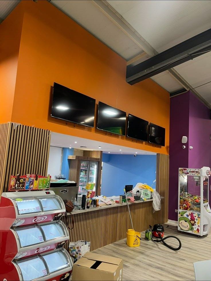 Servery counter with orange feature wall and mounted TVs