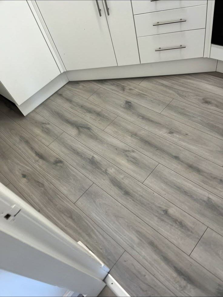 Grey laminate flooring running through a fitted kitchen