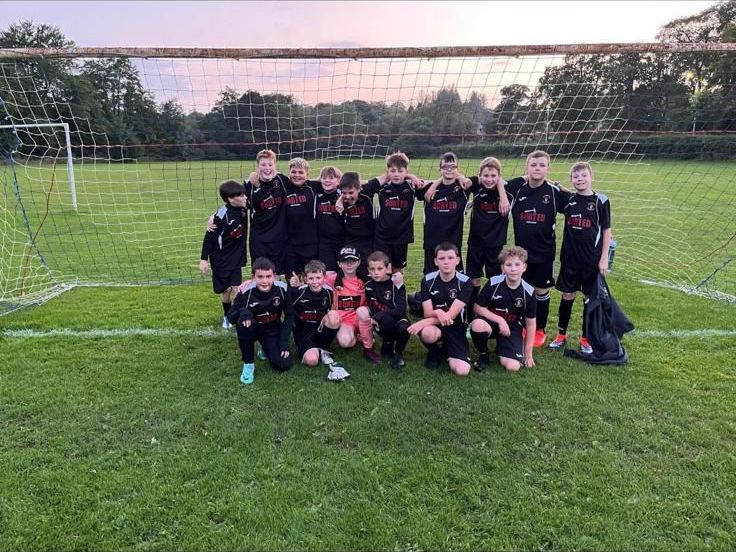 Youth football team lined up at the goal in black SORTED sponsored kits
